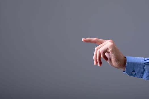 Midsection of caucasian businessman pointing with his finger, isolated on grey background. business technology, communication and growth concept.