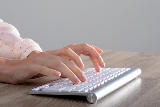 Midsection of caucasian businesswoman typing on keyboard, isolated on grey background. business, technology, communication and growth concept.