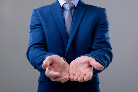 Midsection of caucasian businessman showing his hands, isolated on grey background. business technology, communication and growth concept.