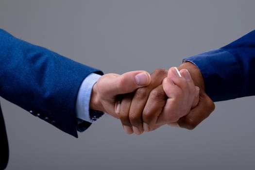 Caucasian and african american business people shaking hands, isolated on grey background. business technology, communication and growth concept.