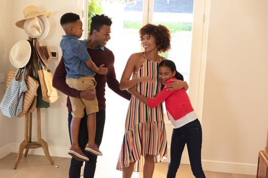Happy african american couple with son and daughter embracing and smiling at home. family enjoying quality free time together.