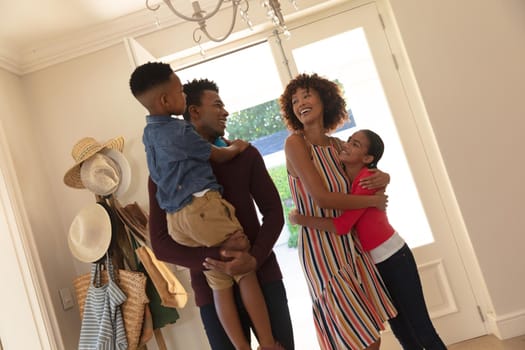 Happy african american couple with son and daughter embracing and smiling at home. family enjoying quality free time together.