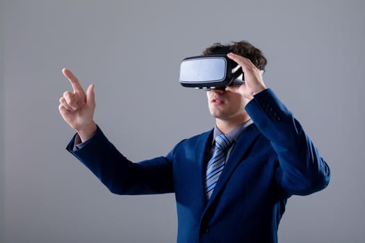 Caucasian businessman wearing vr headset touching virtual interface, isolated on grey background. business technology, communication and growth concept digitally generated composite image.