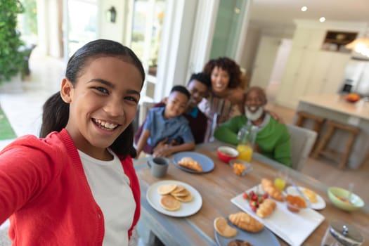 Happy african american family sitting at breakfast table taking selfie and smiling. family enjoying quality free time together.