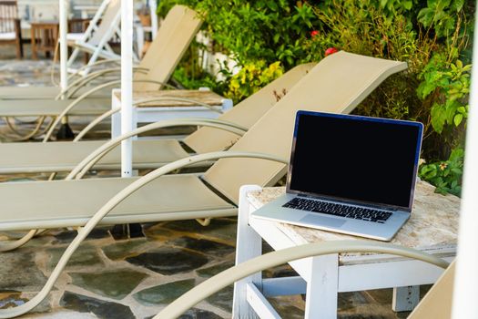 laptop on a sun lounger near the swimming pool.