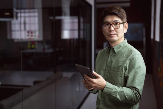 Portrait of asian businessman standing in empty office holding tablet. working in business at a modern office.