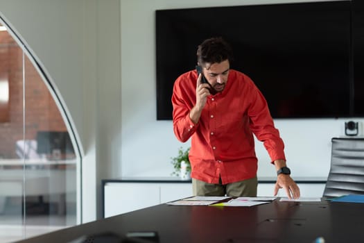 Portrait of caucasian businessman standing in meeting room talking on smartphone. independent creative design business.