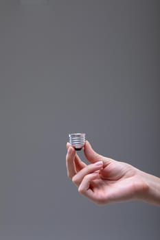 Close up of caucasian businesswoman holding base of light bulb, isolated on grey background. business, technology, communication and growth concept.