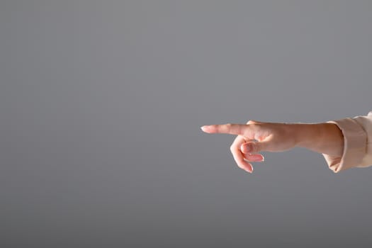 Midsection of caucasian businesswoman pointing with her finger, isolated on grey background. business, technology, communication and growth concept.