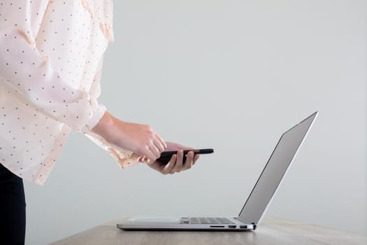 Midsection of caucasian businesswoman using laptop and smartphone, isolated on grey background. business, technology, communication and growth concept.