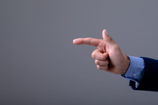 Midsection of caucasian businessman pointing with his finger, isolated on grey background. business technology, communication and growth concept.