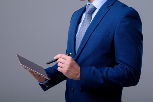 Midsection of caucasian businessman using digital tablet, isolated on grey background. business technology, communication and growth concept.