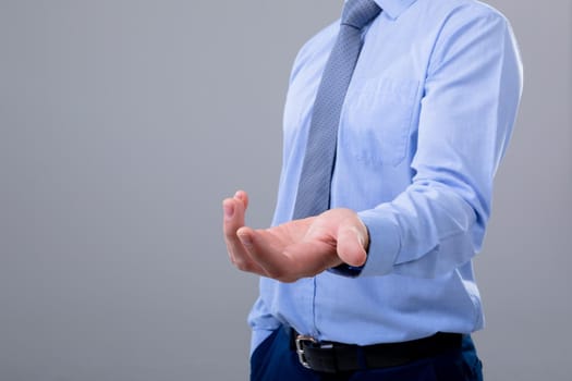 Midsection of caucasian businessman reaching his hand, isolated on grey background. business technology, communication and growth concept.