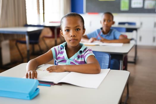 Portrait of african american girl sitting on her desk in the class at school. school and education concept