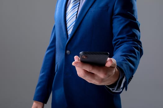 Midsection of caucasian businessman using smartphone, isolated on grey background. business technology, communication and growth concept.