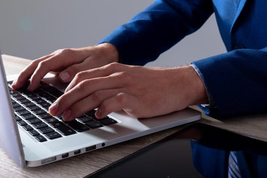 Midsection of caucasian businessman typing on keyboard, isolated on grey background. business technology, communication and growth concept digitally generated composite image.