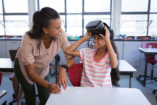 African american female teacher teaching a girl to use vr headset in the class at school. school and education concept