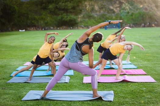 Female teacher and group of diverse students performing stretching exercise in the garden at school. school and education concept