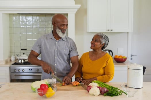 Senior african american couple cooking together in kitchen smiling. retreat, retirement and happy senior lifestyle concept.