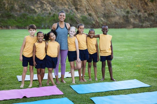 Portrait of female teacher and diverse students smiling while standing together in garden at school. school and education concept