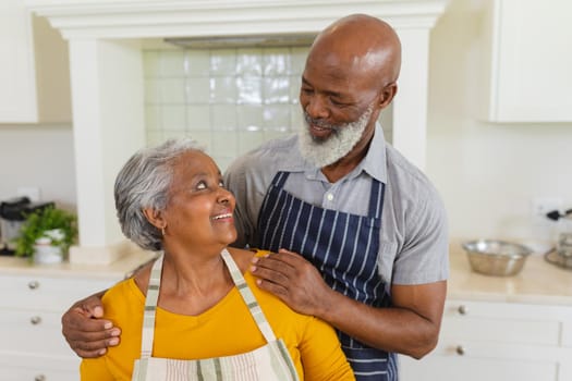 Senior african american couple in kitchen looking at each other and smiling. retreat, retirement and happy senior lifestyle concept.