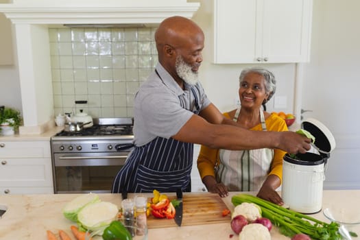 Senior african american couple cooking together in kitchen smiling. retreat, retirement and happy senior lifestyle concept.