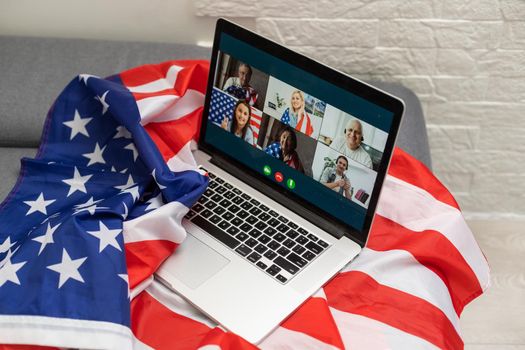 american or usa national flag. working from home on computer notebook laptop on webcam video call conference in quarantine