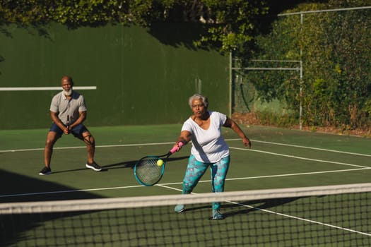 Senior african american couple playing tennis on tennis court. retirement and active senior lifestyle concept.