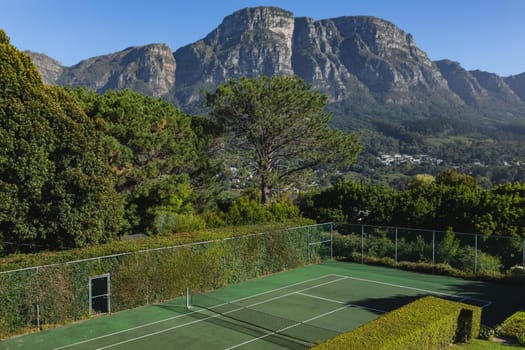 General view of tennis court in stunning countryside on sunny day. retreat, leisure time facilities and active lifestyle concept.