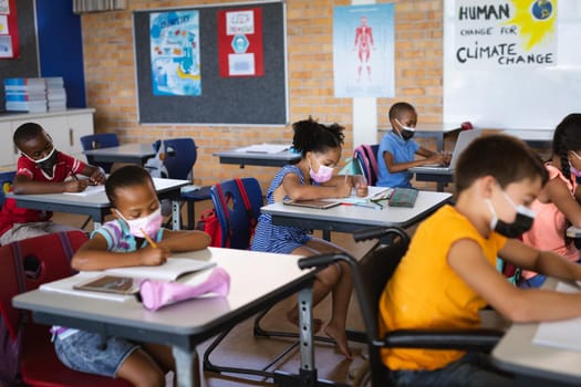 Group of students wearing face masks studying while sitting on their desks at elementary school. education back to school health safety during covid19 coronavirus pandemic.