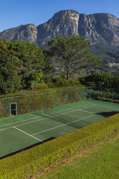 General view of tennis court in stunning countryside on sunny day. retreat, leisure time facilities and active lifestyle concept.