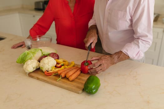 Mid section of senior caucasian couple cooking together in kitchen. retreat, retirement and happy senior lifestyle concept.