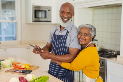 Portrait of senior african american couple cooking together in kitchen using tablet. retreat, retirement and happy senior lifestyle concept.