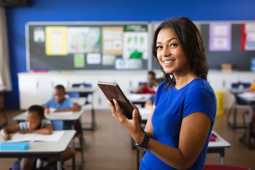 Portrait of african american female teacher holding digital tablet in the class at school. school and education concept