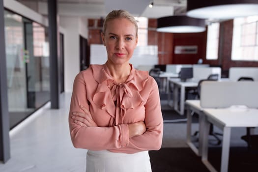 Portrait of caucasian businesswoman standing in office with arms crossed, looking to camera. working in business at a modern office.