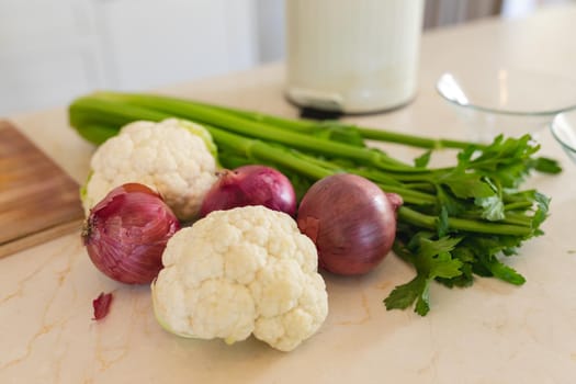 Close up of fresh vegetables lying on white countertop in kitchen. cooking and food concept.