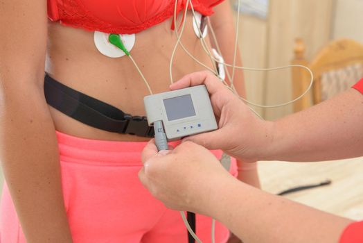 electrocardiography ECG leads for a portable heart monitor on an young woman patient. the nurse connects the ECG device to the patient.