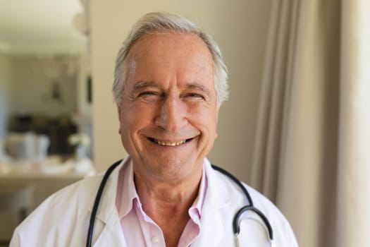 Portrait of senior caucasian male doctor looking at camera and smiling. medicine and healthcare services concept.