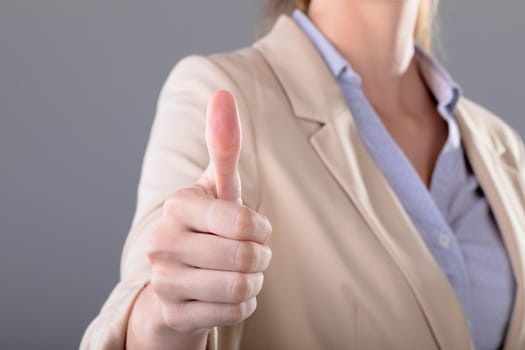 Midsection of caucasian businesswoman touching virtual interface on grey background. business, technology, communication and growth concept.