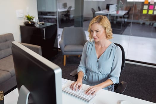 Smiling caucasian businesswoman sitting at desk in office using computer. working in business at a modern office.