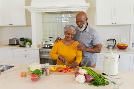 Senior african american couple cooking together in kitchen smiling. retreat, retirement and happy senior lifestyle concept.