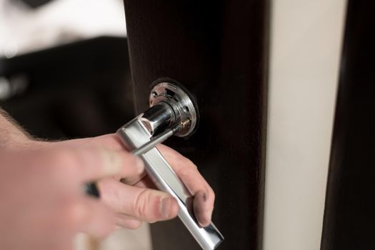 A man installs a handle on a wooden door