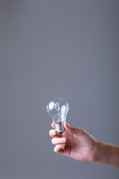 Close up of caucasian businesswoman holding light bulb, isolated on grey background. business, technology, communication and growth concept.