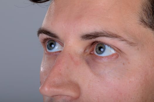 Close up of blue eyes of caucasian businessman, isolated on grey background. business technology, communication and growth concept.