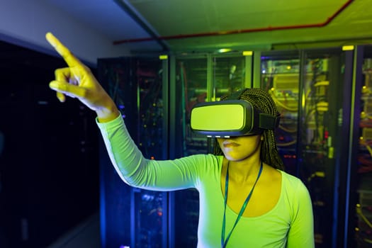 African american female computer technician wearing vr headset and working in server room. digital information storage and communication network technology.