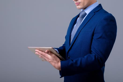 Caucasian businessman using digital tablet, isolated on grey background. business technology, communication and growth concept.