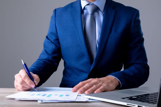 Midsection of caucasian businessman using laptop and taking notes, isolated on grey background. business technology, communication and growth concept.