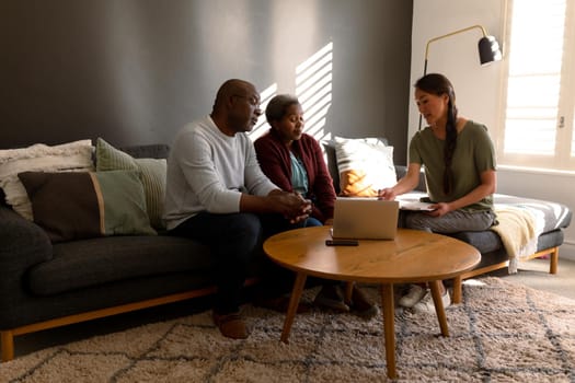 African american senior couple having meeting with asian female financial advisor at home. retirement lifestyle, elderly support and spending time at home.