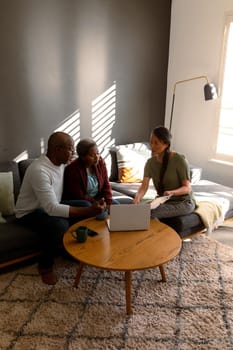 African american senior couple having meeting with asian female financial advisor at home. retirement lifestyle, elderly support and spending time at home.