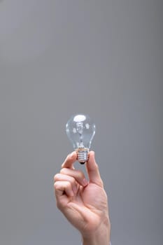 Close up of caucasian businessman holding light bulb, isolated on grey background. business technology, communication and growth concept.